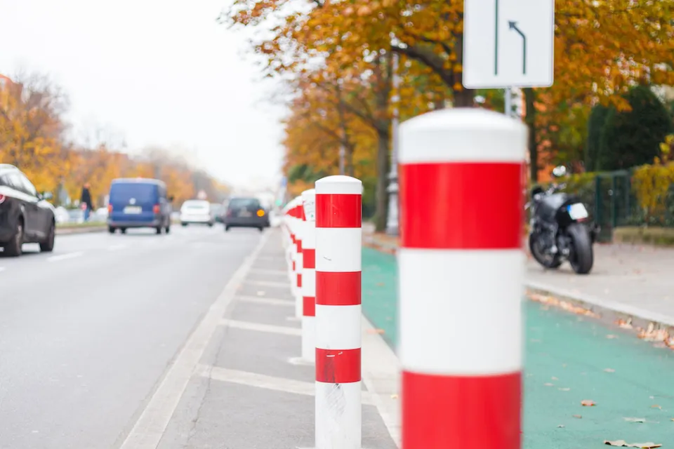 Close-up of white delineators with red stripes denoting green painted bike lane in Berlin, Germany.